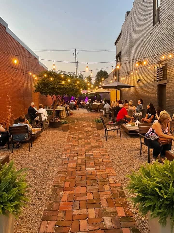 A full Reno Tavern patio on a summer evening under string lights, with live music at the far end