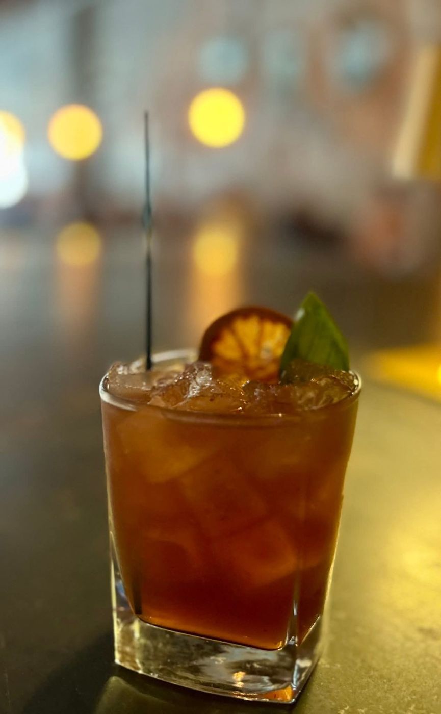 A house cocktail with dried orange and basil