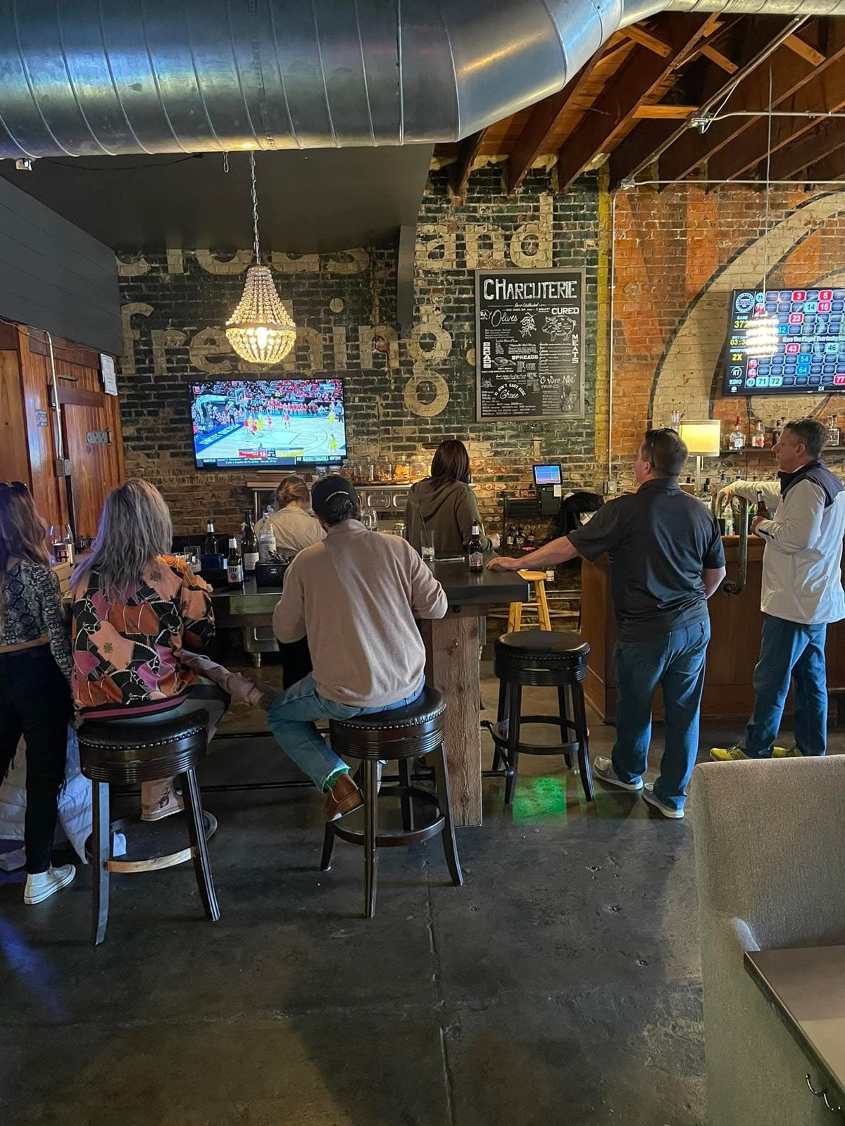 Guests watching the game at the bar under the Coca-Cola ghost sign and a crystal chandelier