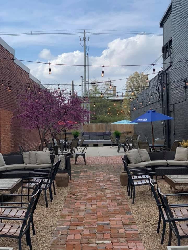 The Reno patio in spring with a blooming redbud tree, café lights and a brick walkway