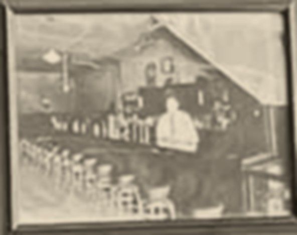 Vintage photo of Don Brouillette, the Reno’s original owner, standing behind the original bar with a row of stools in front